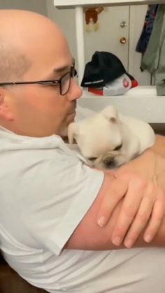 a man holding a small white dog in his arms