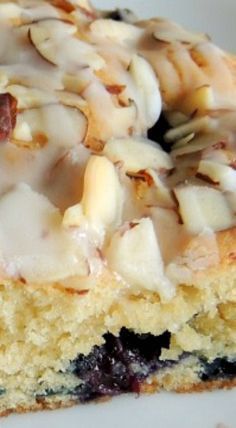 a piece of cake with icing and nuts on it sitting on a white plate