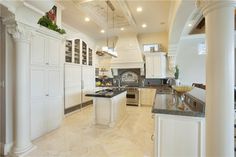 a large kitchen with white cabinets and marble counter tops