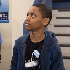 a young boy sitting in front of a water dispenser looking up at the sky