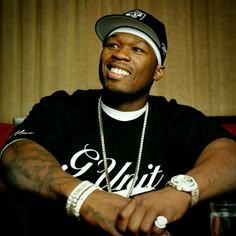 a man sitting on top of a red couch wearing a black shirt and white hat