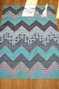 a blue and gray chevroned quilt on a wooden floor