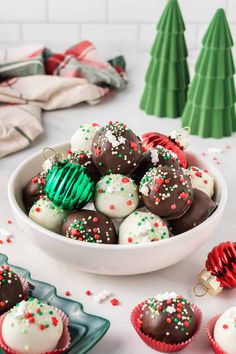 a white bowl filled with chocolate covered christmas treats next to small green and red ornaments