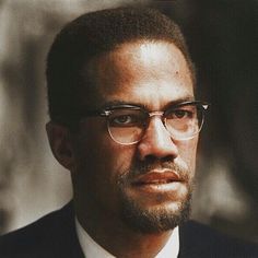 a man wearing glasses and a suit looks at the camera