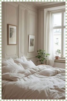 an unmade bed with white sheets and pillows in front of a window next to a potted plant