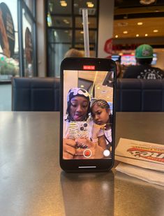 a cell phone sitting on top of a table next to a woman holding a child