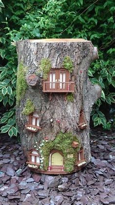 a tree stump with a house built into it's side and some plants growing on the top