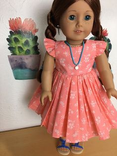 the doll is wearing a pink dress with white flowers on it, and blue shoes