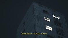 the words sometimes i dream of you are projected in front of a tall building at night