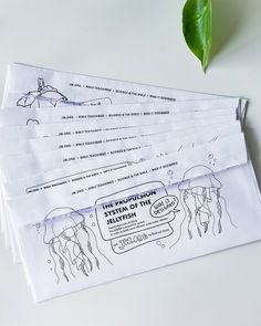 three envelopes with drawings on them sitting next to a plant