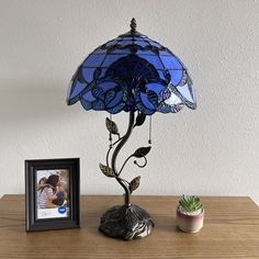 a blue lamp sitting on top of a wooden table next to a potted plant