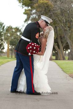 a bride and groom kissing on the sidewalk