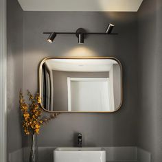 a bathroom sink sitting under a mirror next to a vase with flowers