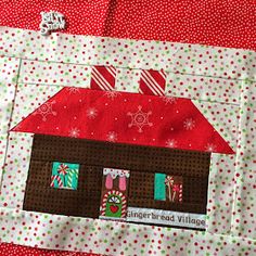 a red and white quilted house with gingerbread village on it's side