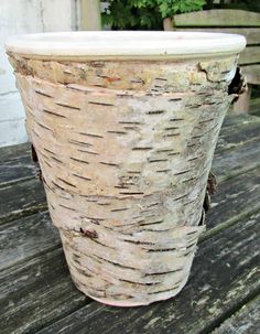 a large white vase sitting on top of a wooden table next to a planter