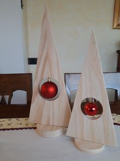 two wooden christmas trees with red ornaments on top of each one, sitting on a table