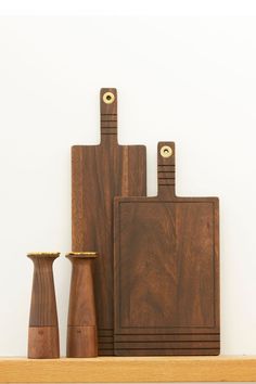 wooden cutting boards and vases sit on a shelf in front of a white wall