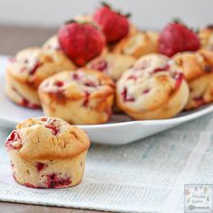 strawberry muffins on a white plate with strawberries in the background and napkin