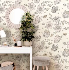 a white desk with a mirror, stool and plant in front of the wallpaper