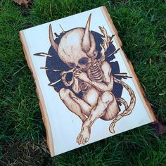 a drawing of a skeleton sitting on top of a piece of wood in the grass