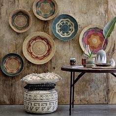 several plates are hanging on the wall next to a small table with a plant in it