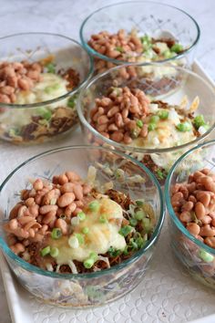 four glass bowls filled with food on top of a table