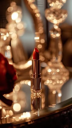 a red lipstick sitting on top of a table next to some wine glasses and candles