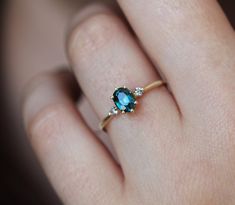 a woman's hand with a ring on it that has an oval blue stone in the middle