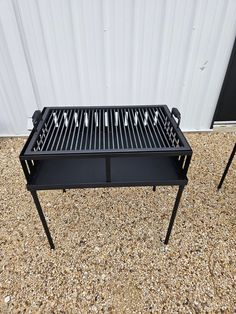 two black grills sitting on top of a gravel ground