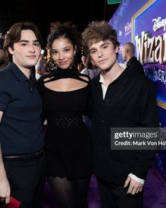 three people standing next to each other on a purple carpet