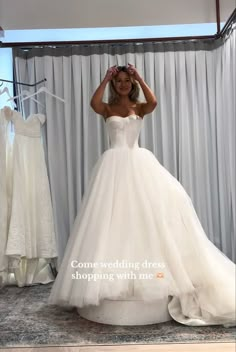 a woman standing in front of a wedding dress