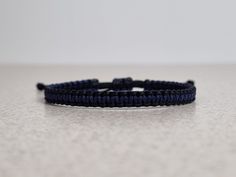 a close up of a blue bracelet on a white table with a black bead around it