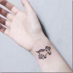 a small tattoo on the wrist of a woman's hand, with an unicorn