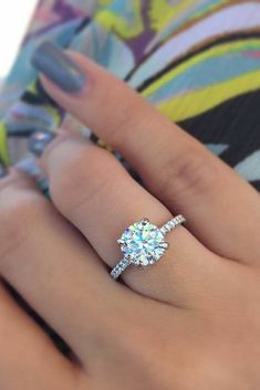 a woman's hand with a diamond ring on top of her finger and an engagement band