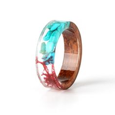 a wooden ring with blue and red flowers inlayed to the inside, on a white background