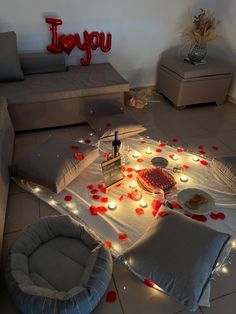 a living room filled with lots of furniture covered in red rose petals and lit candles