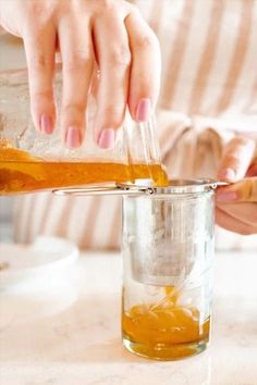 a person pouring liquid into a glass on top of a table