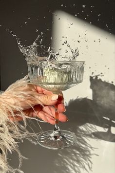 a person holding a wine glass with water splashing out of the top and bottom