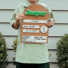 a young boy holding up a sign that says jasper and has numbers on it