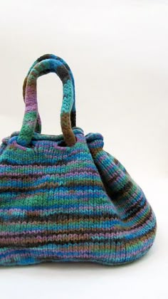 a multicolored knitted purse sitting on top of a white table next to a wall