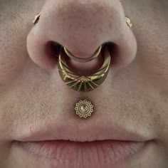 a woman's nose is adorned with gold jewelry