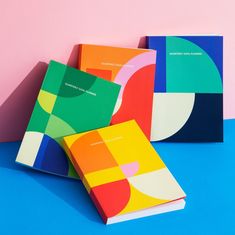 three different colored books sitting on top of a blue and pink surface next to each other