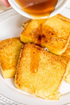 someone is pouring syrup on some toasted bread with other pieces in the foreground