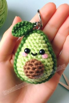 a crocheted keychain with a green apple on it's face