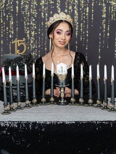 a woman wearing a tiara standing in front of a table with candles