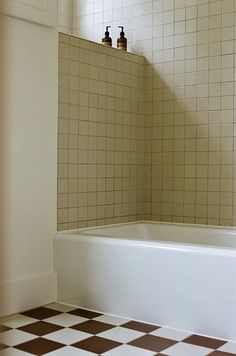 a bath tub sitting next to a window in a bathroom with checkered flooring