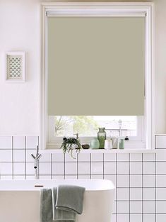 a white bath tub sitting under a window in a bathroom