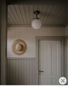 a hat is hanging on the wall next to a door with a light above it