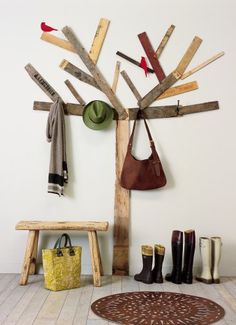 a tree made out of wooden planks with boots hanging on it and a bag next to it