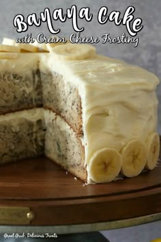 a banana cake with cream cheese frosting is cut into slices and sits on a wooden platter